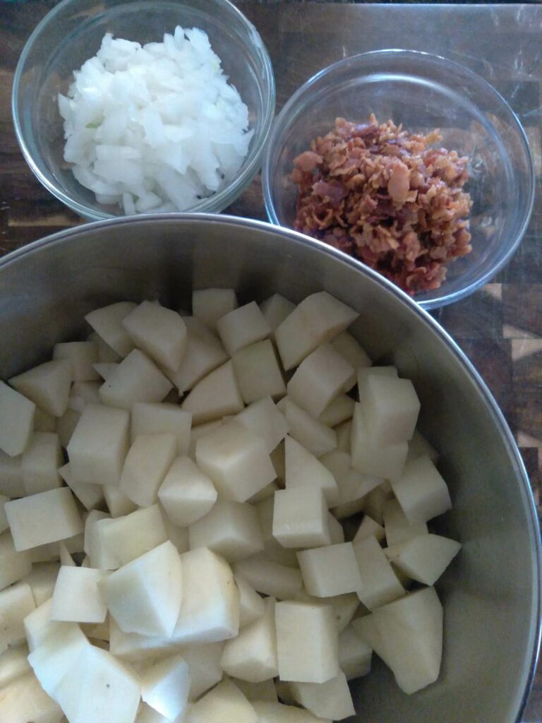 image of potatoes, bacon, and onions on a cutting board.