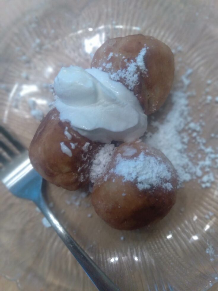 image of fried cherry dumplings topped with powdered sugar and sour cream.