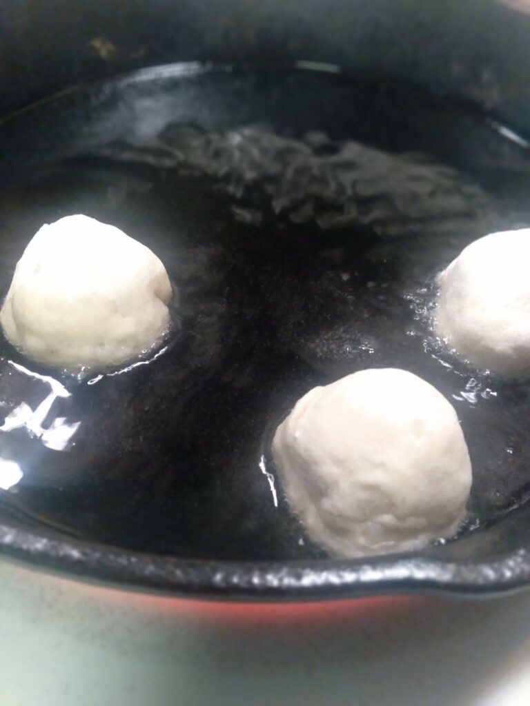 image of frying pan with cherry dumplings with potato bread in them.