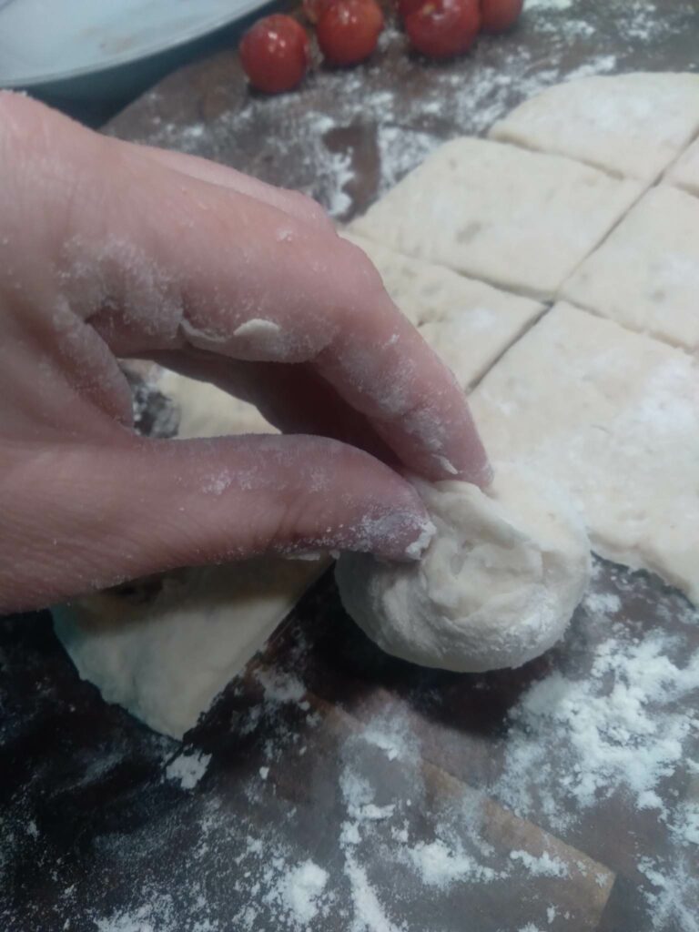 image of fingers pinching dough around cherry.