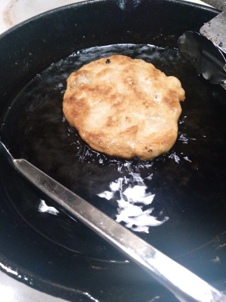 image of potato langos frying in a pan.